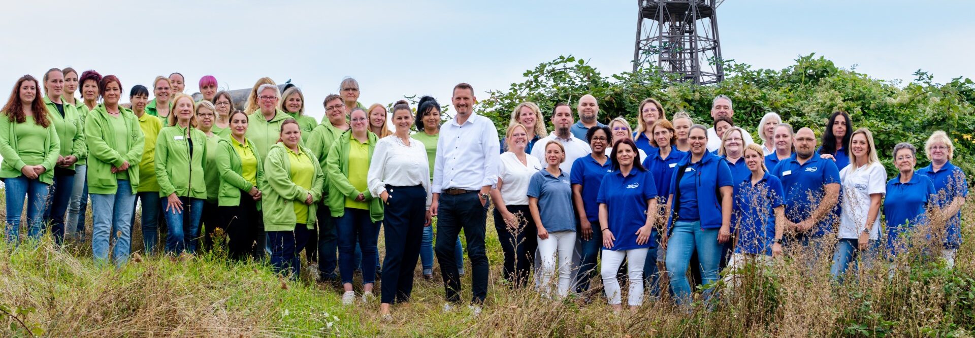 Die Teams der Gloger Pflege und der Gloger Hausdienste auf einer Wiese vor dem Ilseder Wasserturm