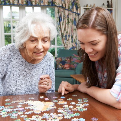 Eine ältere und eine junge Frau sitzen an einem Tisch und puzzeln