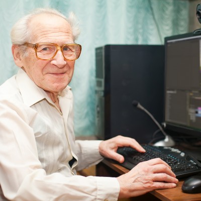 Ein älterer Mann sitz vor einer Tastatur und einem Monitor